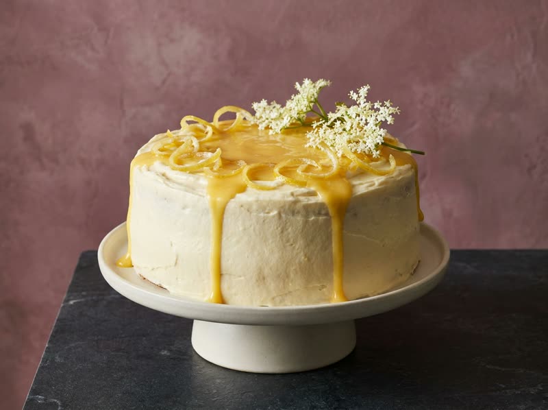Lemon and elderflower cake topped with lemon curd, candied zest curls and elderflower blossoms