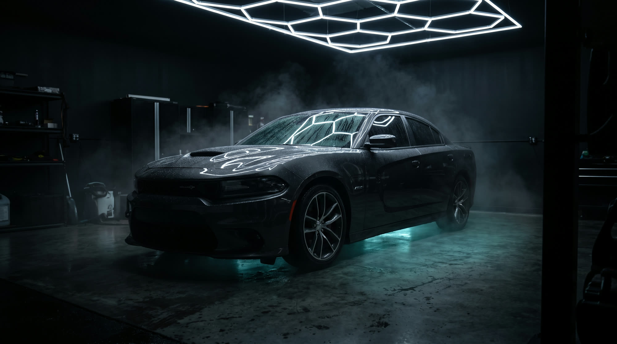 A dark sedan beaded with water under a hexagonal light ceiling